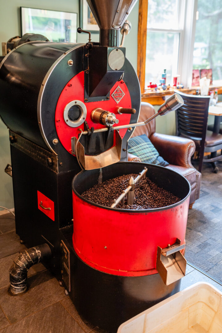 A red coffee roaster with beans in it.